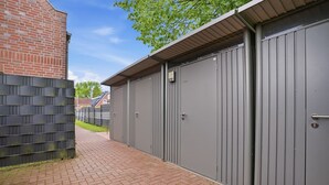 A pathway leading to a building with grey metal doors and a brick wall.