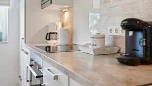 A modern kitchen with a built-in oven, a coffee maker, and a sugar container on the counter.