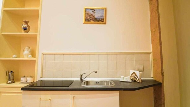 A kitchen with a black countertop, a sink, and a small framed picture on the wall. - Neapolitan House - Culture Apartament (Napoli)