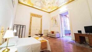 A hotel room with a bed, a desk, a chair, a sofa, and a balcony. - Neapolitan House - Culture Apartament (Napoli)