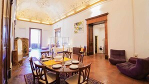A spacious living room with a high ceiling, a dining area with a round table and chairs, and a seating area with sofas. - Neapolitan House - Culture Apartament (Napoli)