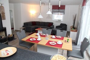 Una sala de estar moderna con un sofá, una mesa de comedor para cuatro personas y una chimenea.