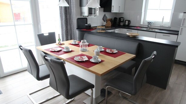 A modern kitchen with a dining table set for four, equipped with a microwave, coffee maker, and a kettle. - Fiete - Beautiful vacation home directly in the village center! (Krummhörn)