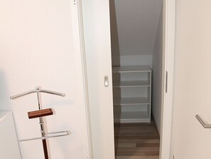 A hallway leading to a closet with shelves.