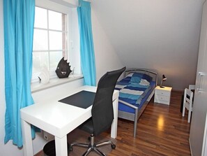 A bedroom with a bed, a desk, and a chair. - Nordlicht - Holiday home (100sqm) for 6 people with fireplace and garden in a central location. (Norden)