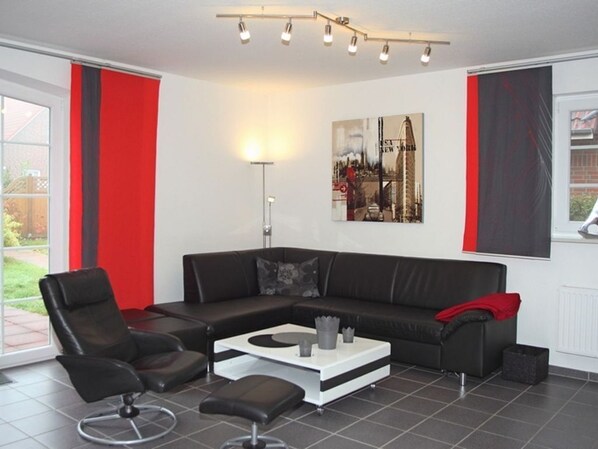 Ein modernes Wohnzimmer mit einem schwarzen Ledersofa, einem weißen Couchtisch und einer Stehlampe.