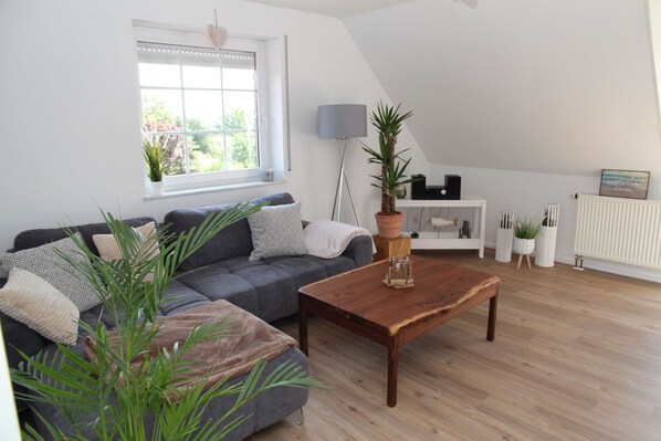 A modern living room with a grey sofa, a wooden coffee table, and a large window.