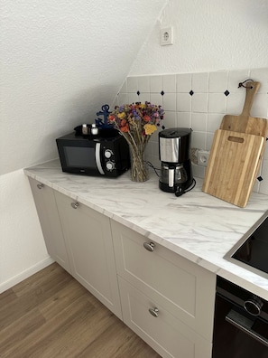 Eine Küche mit Marmorarbeitsplatte, einer Kaffeemaschine, einem Toaster und einem Holzschneidebrett.