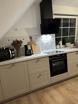 A modern kitchen with a built-in oven, microwave, and coffee maker. - Deichblick 2 - High-quality vacation apartment with a wonderful view of the countryside (Krummhörn)