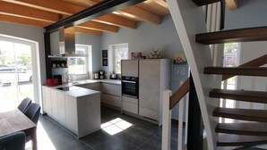 A modern kitchen with a central island, built-in appliances, and large windows. - Dat Hygge Huus - New vacation home in the immediate vicinity of the cutter harbor (Krummhörn)