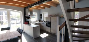 A modern kitchen with a central island, built-in appliances, and large windows. - Dat Hygge Huus - New vacation home in the immediate vicinity of the cutter harbor (Krummhörn)