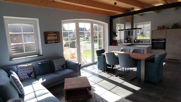A modern living room with a sofa, coffee table, and dining area with chairs. - Dat Hygge Huus - New vacation home in the immediate vicinity of the cutter harbor (Krummhörn)