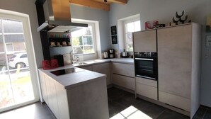A modern kitchen with a built-in island, a double oven, and a large refrigerator. - Dat Hygge Huus - New vacation home in the immediate vicinity of the cutter harbor (Krummhörn)
