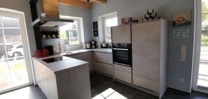 A modern kitchen with a built-in island, a double oven, and a large refrigerator. - Dat Hygge Huus - New vacation home in the immediate vicinity of the cutter harbor (Krummhörn)