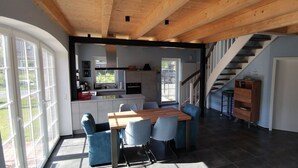 A modern kitchen with a dining area, wooden ceiling beams, and a staircase. - Dat Hygge Huus - New vacation home in the immediate vicinity of the cutter harbor (Krummhörn)