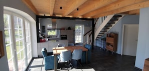 A modern kitchen with a dining area, wooden ceiling beams, and a staircase. - Dat Hygge Huus - New vacation home in the immediate vicinity of the cutter harbor (Krummhörn)