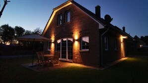 A brick house with a patio, a dining table, and chairs. - Dat Hygge Huus - New vacation home in the immediate vicinity of the cutter harbor (Krummhörn)
