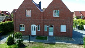 A two-story brick house with a symmetrical facade, white-framed windows, and a central chimney. - Anchorage - Family-friendly semi-detached house in a quiet location (Krummhörn)
