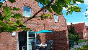 A brick house with a patio area featuring a table and chairs under a blue umbrella. - Anchorage - Family-friendly semi-detached house in a quiet location (Krummhörn)