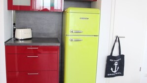 A compact kitchen with red cabinets, a yellow refrigerator, and a white door. - Anchorage - Family-friendly semi-detached house in a quiet location (Krummhörn)