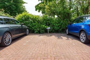 A parking area with two cars, a brick pavement, and a sign. - Gode Stuuv - Our "good room" (75sqm) for 4 persons centrally located in Greetsiel (Krummhörn)