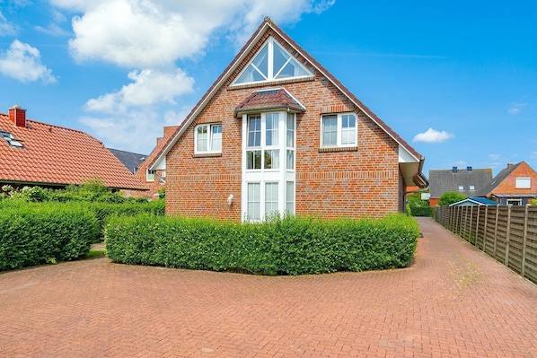 A two-story brick house with a gabled roof, a central entrance, and a small front garden.