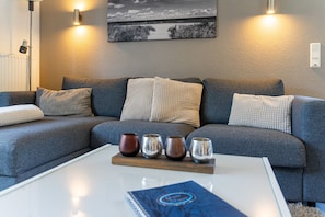 A modern living room with a grey sofa, a white coffee table, and decorative vases.