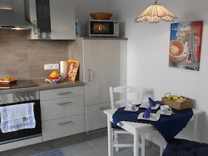 Eine moderne Küche mit Mikrowelle, Backofen und Essbereich, gedeckt für zwei Personen.