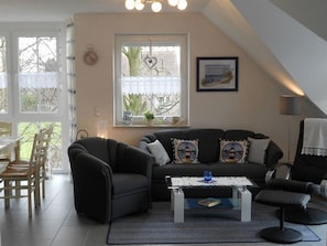 Ein gemütliches Wohnzimmer mit einer dunklen Couch, einem Couchtisch und einem Essbereich mit Stühlen.
