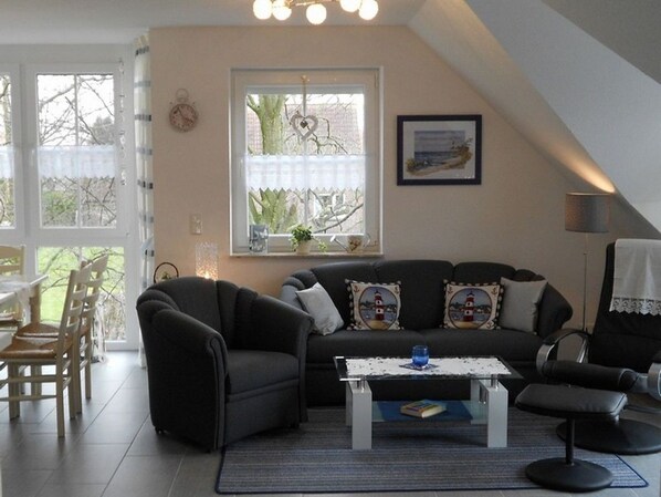 Ein gemütliches Wohnzimmer mit einer dunklen Couch, einem Couchtisch und einem Essbereich mit Stühlen.