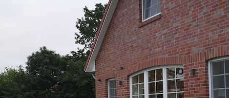A brick house with a patio, a table, and chairs.