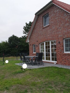 Ein Backsteinhaus mit Terrasse, Tisch und Stühlen.