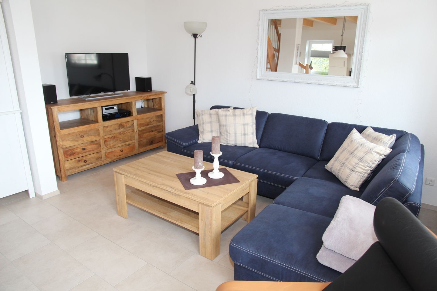 A living room with a blue sofa, wooden coffee table, and a TV on a wooden cabinet.