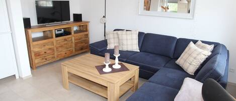 A living room with a blue sofa, wooden coffee table, and a TV on a wooden cabinet.