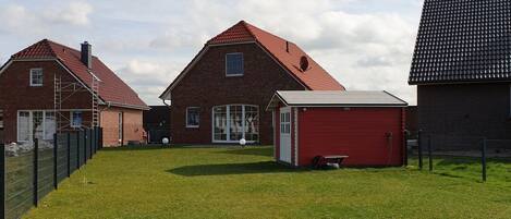 A residential area with brick houses, a red garage, and a fenced yard.