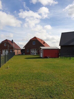 Un quartier résidentiel avec des maisons en briques, un garage rouge et une cour clôturée.