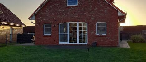 A brick house with a large front porch and a well-maintained lawn.