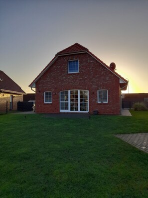A brick house with a large front porch and a well-maintained lawn.