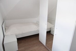 A bedroom with a single bed, a nightstand, and a wardrobe. - Bei Ruhe - Beautiful vacation home in a fantastic waterfront location (Hinte)