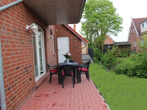 Une maison en briques avec un patio comprenant une table et des chaises.