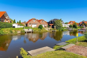 Un canal con casas a un lado y un muelle de madera al otro.