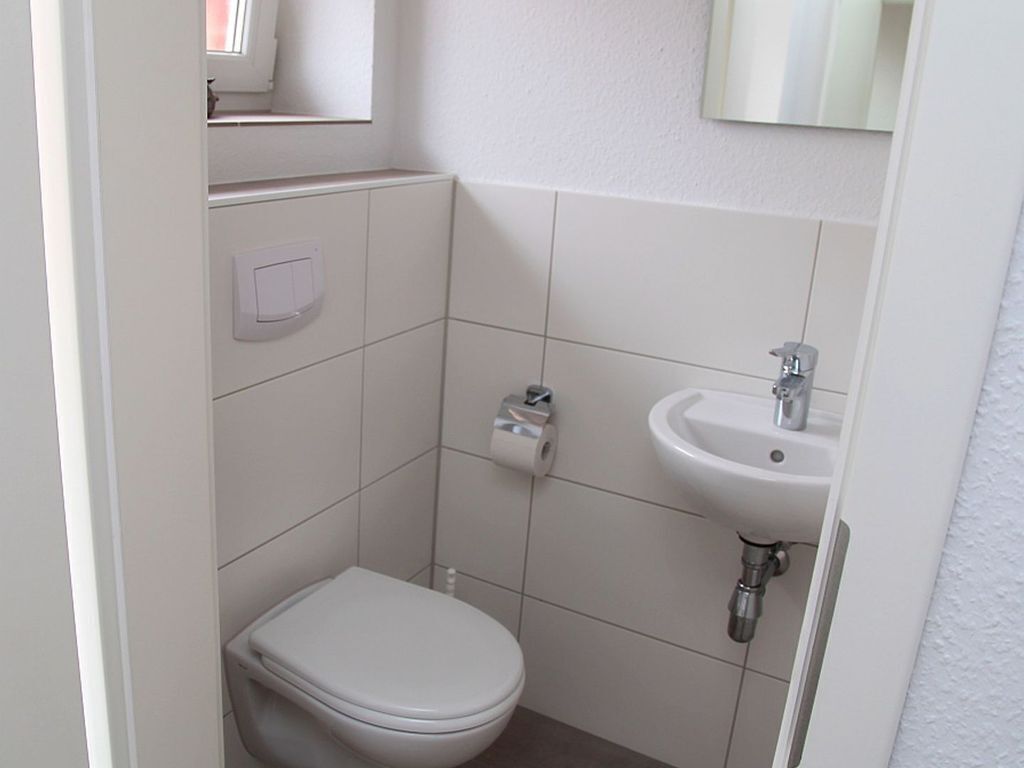 Un baño pequeño y limpio con inodoro, lavamanos y espejo.