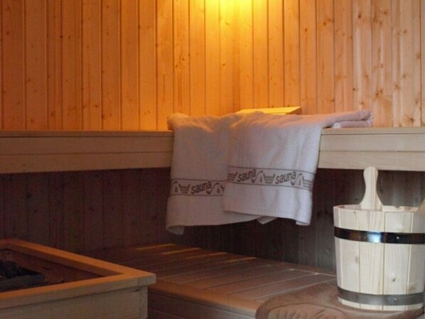 Un cuarto de sauna con paredes de madera, un banco y toallas colgadas en un perchero.