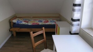 A small room with a wooden bench, a white table, and a colorful floral bedspread. - MaiStern - High-quality vacation home (100sqm) for 6 people with fireplace, sauna & (Sternberg)