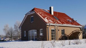 A two-story house with a red-tiled roof, a brick exterior, and a garage. - MaiStern - High-quality vacation home (100sqm) for 6 people with fireplace, sauna & (Sternberg)