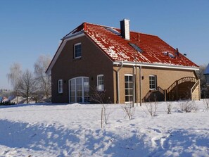 A two-story house with a red-tiled roof, a brick exterior, and a garage.