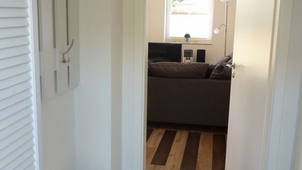 A narrow hallway leading to a bedroom with a bed, a bedside table, and a window. - MaiStern - High-quality vacation home (100sqm) for 6 people with fireplace, sauna & (Sternberg)