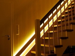 Una escalera de madera con barandilla, iluminada con luz cálida.