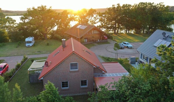 A two-story brick house with a red roof, a covered porch, and a solar panel on the roof. - MaiStern - High-quality vacation home (100sqm) for 6 people with fireplace, sauna & (Sternberg)