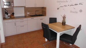 Une cuisine moderne avec des meubles blancs, un four à micro-ondes et un évier. On y trouve une table à manger avec des chaises et une carte géographique accrochée au mur.